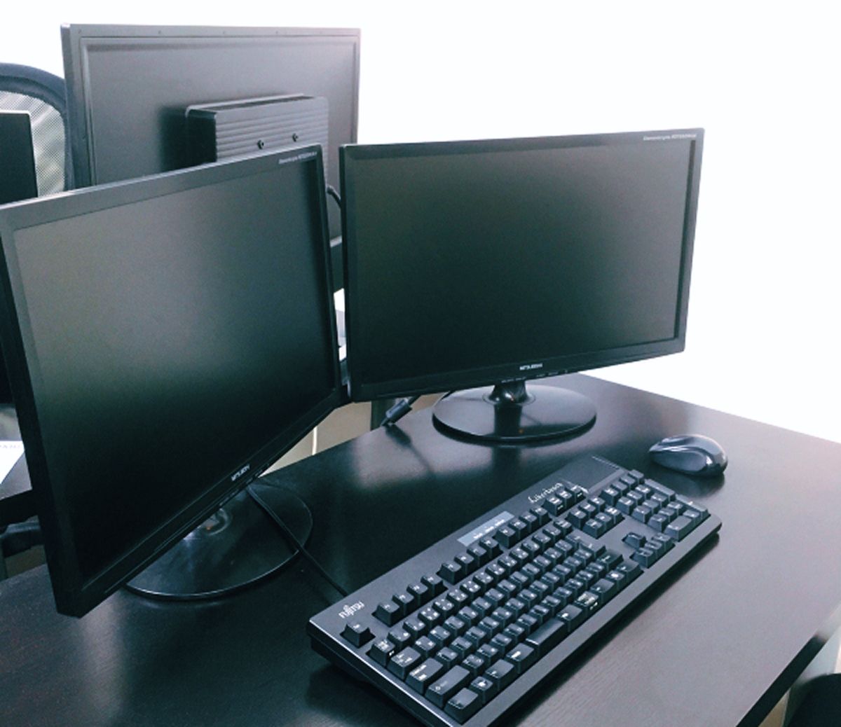 黒のテーブルの上にディスプレイが2枚あり、その手前にキーボードとマウスが並んでいる