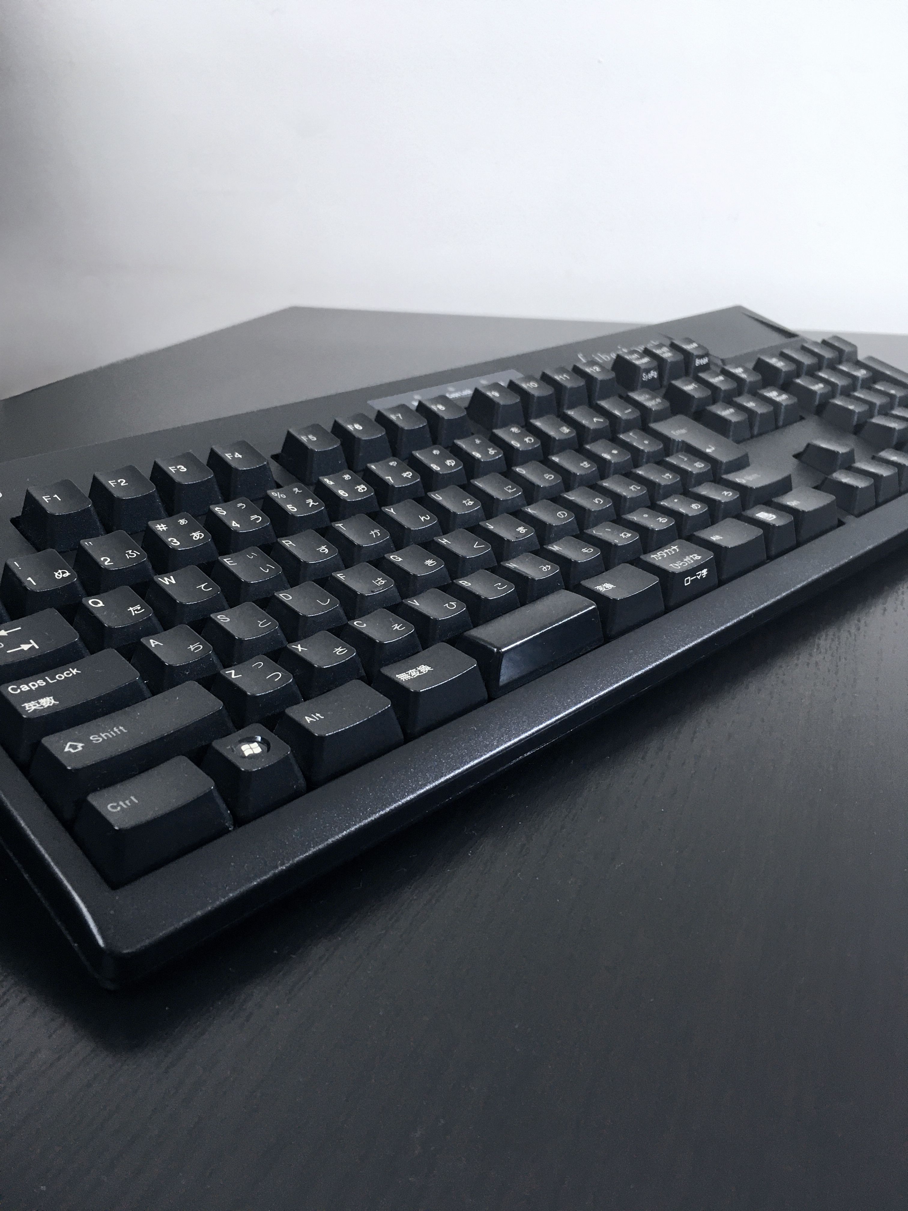 黒のテーブルの上に黒いキーボードが置いてある